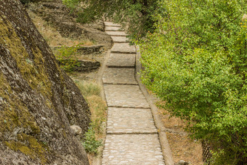 paves upstairs narrow road path way between trees and rock in south park outdoor natural environment