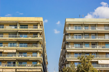 common apartment building symmetry facade of front side with balcony and windows on clear blue sky background