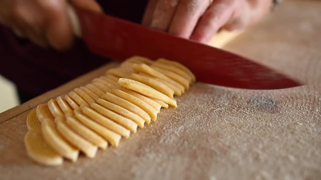 A woman is making fresh pasta called 'Fettuccine' made from fresh eggs and durum wheat flour. Fettuccine is a flat thick pasta popular in Roman and Tuscan cuisine.