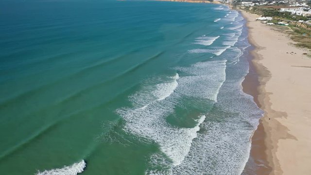 Top view Athlantic ocean waves reaching South Spain sand beach shore drone aerial