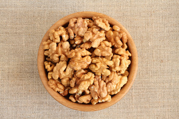 Big shelled walnuts in bamboo bowl on rough gray linen cloth