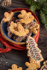 Christmas holiday background with gingerbread cookies, candy canes and evergreens over wooden table. Christmas and New year food. Christmas decoration and sweets on wood background.