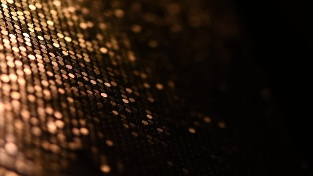 Golden metallic glitter fabric surface rotation. Holiday abstract glitter background with blinking lights. Sequin backdrop. Slow motion. 4K UHD video footage. 3840X2160