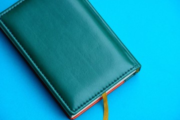 green notepad with leather cover on a blue background