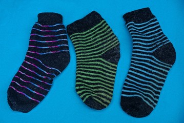 three colored old striped woolen socks on a blue table