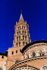 Tower of Basilica of Saint-Sernin against blue sky, in old town of Toulouse, France