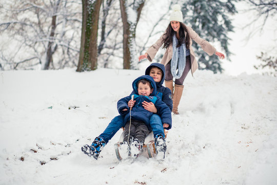 Young Mom Chasing Her Cute Sons While They Are Sledding