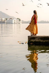 Lonely indian woman in a beautiful dress looks at the lake in Udaipur, Rajasthan, India