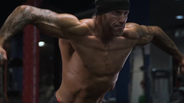 Adult male athlete with tattoos on his arms exercising in the gym.