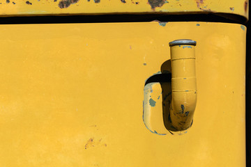 Gas tank pipe and cap on a rusty yellow antique truck