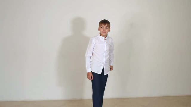 Cheerful little boy in black pants and white shirt jumping on white background in Studio. Slow motion.