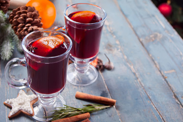 Two wineglass with Christmas mulled red wine with spices and fruits on a wooden rustic table.
