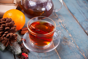 Drink of apple tea with cinnamon stick, star anise and clove. Seasonal punch in cup on wooden background.