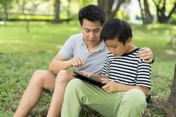 Little boy with father play game on tablet