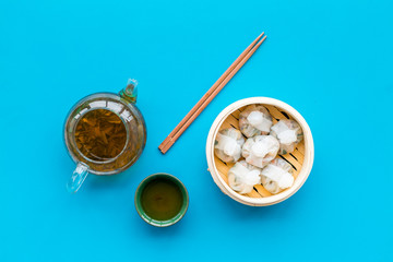 Chinese food set with dim sum, sticks and tea on blue background top view