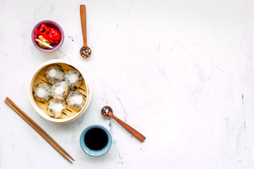 Dim sums with red pepper and vegetables with sticks and black tea in Chinese restaurant on marble background top view mockup