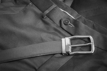 Black and white view of black leather belt kept on a formal pant trouser