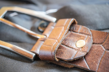 Close up of buckle of a brown textured leather belt kept on a pant trouser