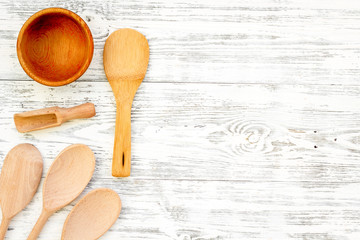 Fork, spoon, bowl in woodenware set on light wooden background top view space for text