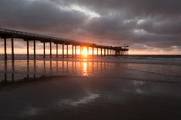 Fototapeta na wymiar Sunset through the Scripps Pier on the beach in La Jolla, California