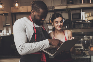 Barista man and woman looking at a laptop