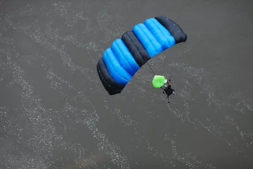 Fototapeten Base jumper under the canopy of a parachute in the background of the water surface. View from above. © esalienko