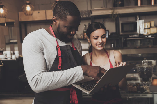Barista man and woman looking at a laptop
