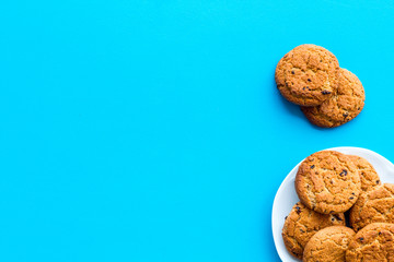 Homemade oatmeal cookies on white plate on blue background top view space for text