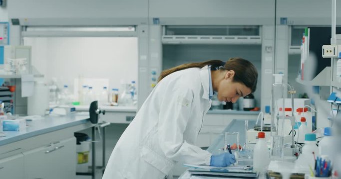 Portrait of female scientist make analysis of the DNA and molecules in the test tubes and signs results in laboratory. Shot in 8K. Concept: research,biochemistry, pharmaceutical medicine