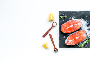 Raw salmon fish on black plates for cooking steaks on white restaurant kitchen background top view space for text