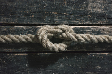 Fototapeta premium Rope knot on the wooden surface background.