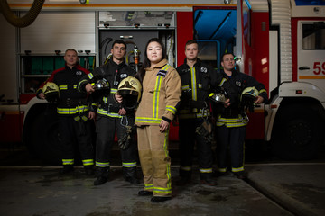 Image of four male and female firefighters on background of fire truck