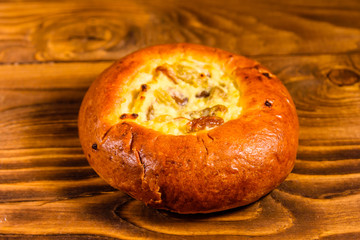 Sweet bun with cottage cheese and raisins on wooden table