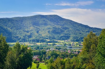 Beautiful green mountain rural landscape. Cottages under beautiful hills in the summer scenery.