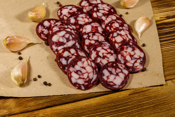 Sliced salami sausage on brown paper on wooden table