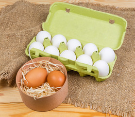 Different chicken eggs in wooden box and paper pulp carton