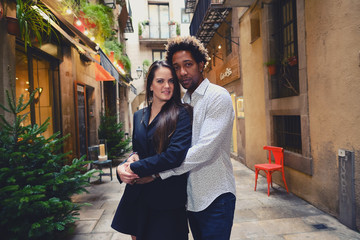 Una pareja feliz y enamorada interracial en las calles de Barcelona pasando un día bonito.