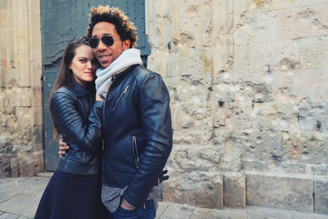 Una pareja feliz y enamorada interracial en las calles de Barcelona pasando un día bonito.