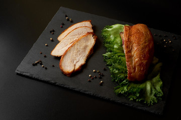 Roasted, sliced chicken breast on a black slate plate.