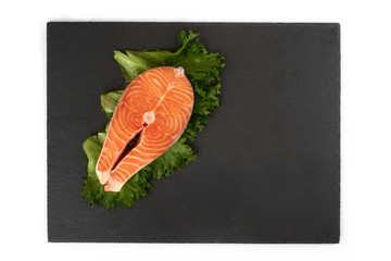 fresh salmon steak on a slate plate , isolated on a white background.