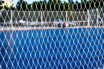 Blue plastic pitch. Look through the white mesh.