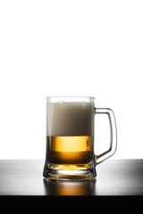 Frosty mug of light beer on wood table