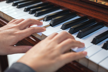Obraz premium Closeup image of hands playing a vintage wooden grand piano