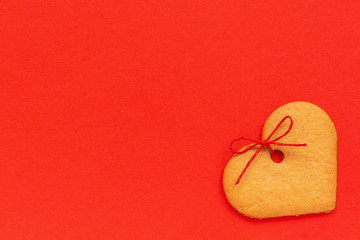 Ginger cookies heart-shaped decorated with a bow on a red background. Top view Copy space Valentine card