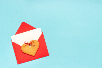 Red envelope with blank white card for text and heart shaped ginger cookies on blue background. Top view Copy space Mock up Concept letter greetings with love