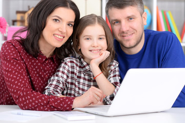 Close up portrait of parents and daughter using laptop in room
