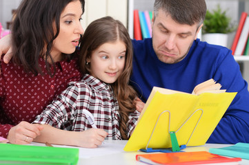 Obraz premium Close up portrait of parents and daughter doing homework