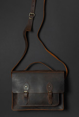 Fashionable concept. Brown leather men's bag on black background top view flat lay with copy space....
