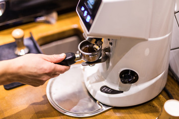 Cropped image of barista grinding fresh coffee into bayonet in coffee shop