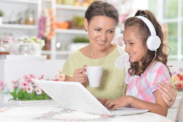 Portrait of happy mother and daughter using laptop together
